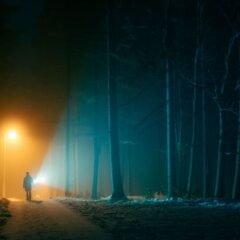 Людина з ліхтарем на стежці в туманному лісі вночі