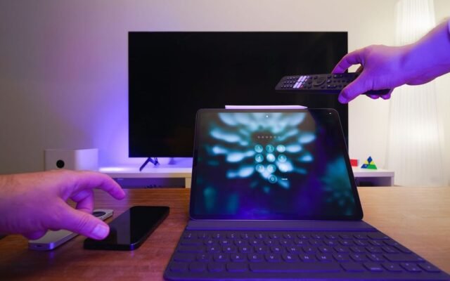 Телевізор, планшет і пульт у вітальні з фіолетовим підсвічуванням