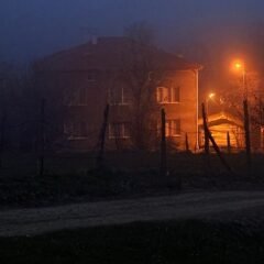 Самотній будинок у нічному тумані із яскравим помаранчевим світлом ліхтаря