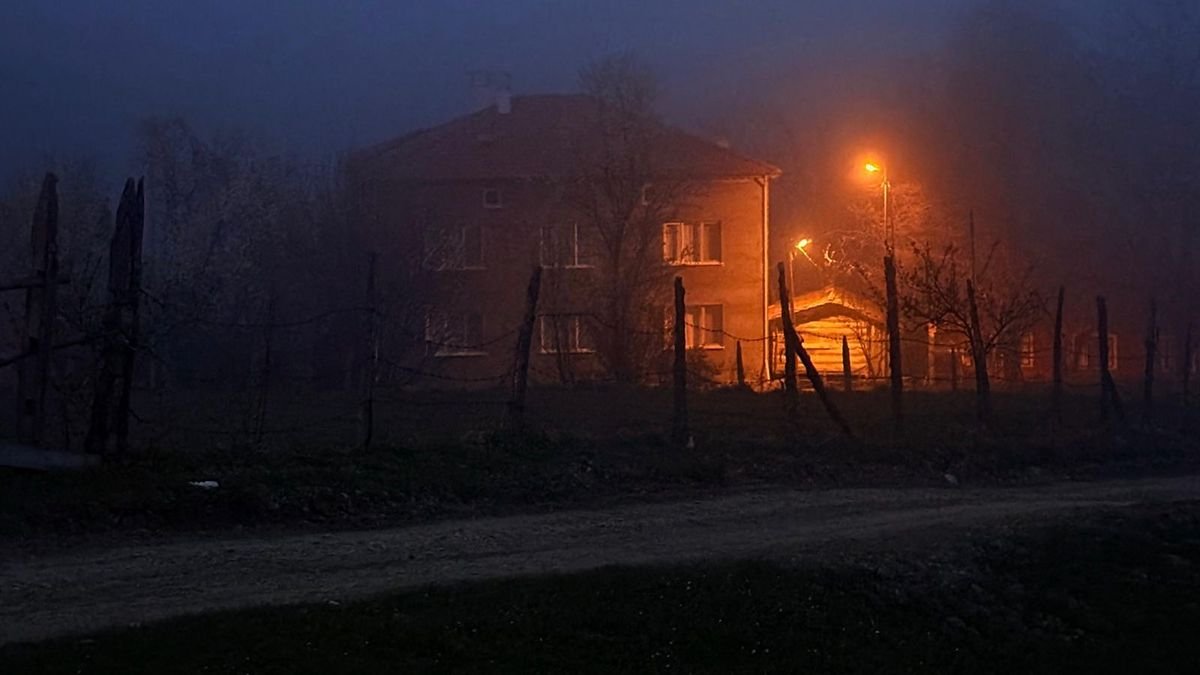 Самотній будинок у нічному тумані із яскравим помаранчевим світлом ліхтаря